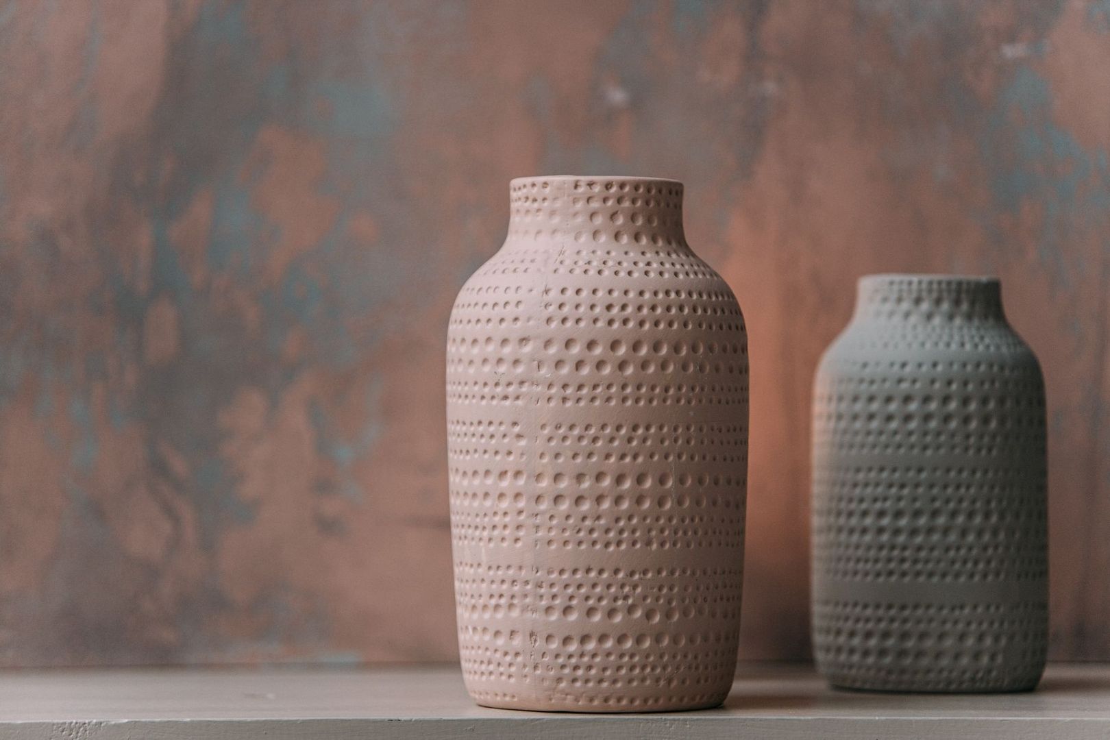 Deux vases en céramique texturée posés sur une étagère