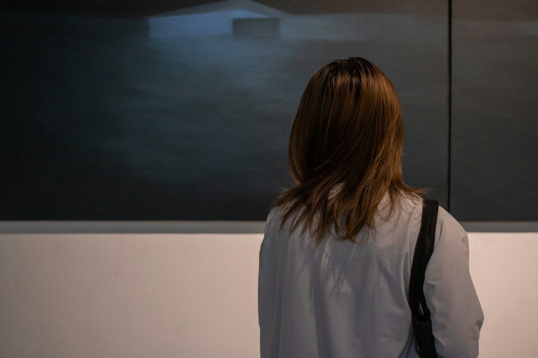 Visiteuse observant une grande œuvre sombre dans une galerie